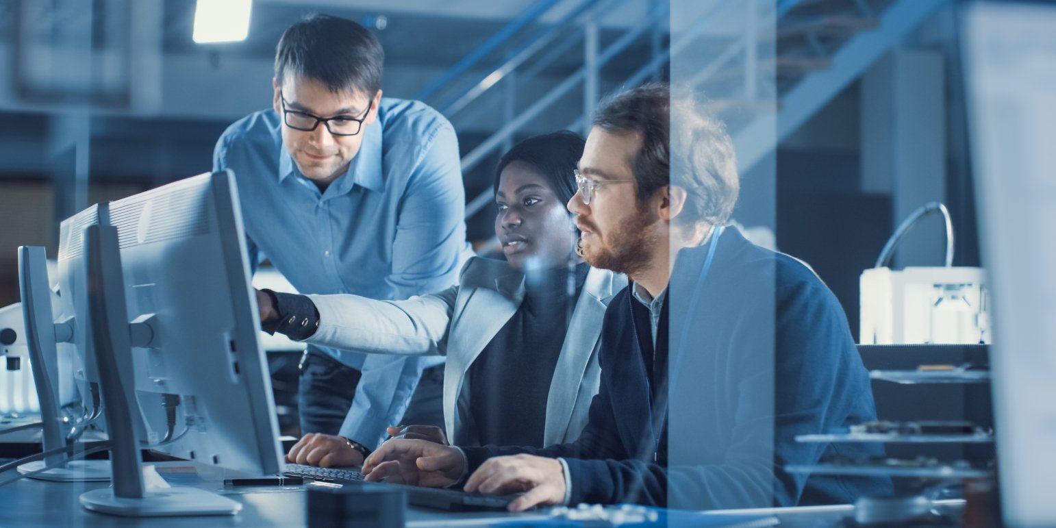 3 people around a computer in an office